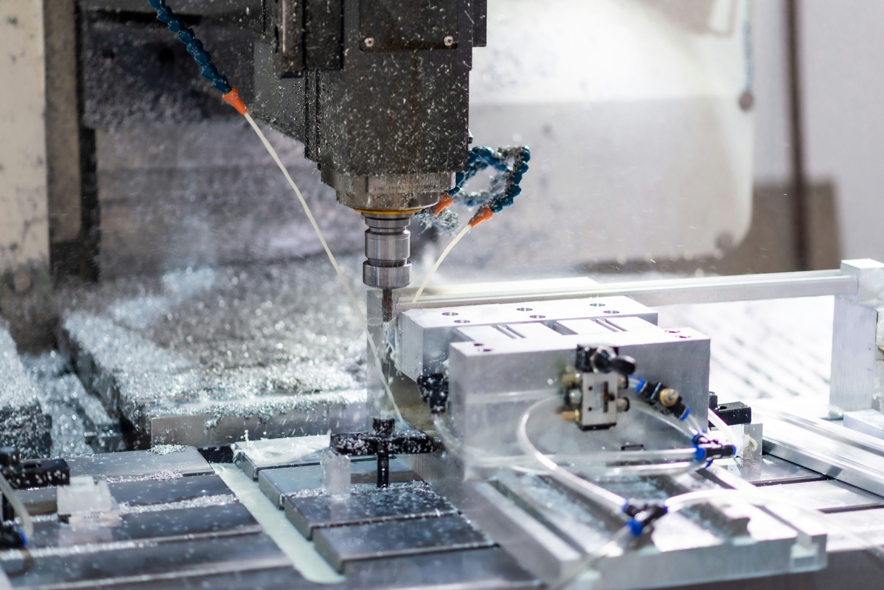 CNC machine cutting a precision part, coolant spray visible